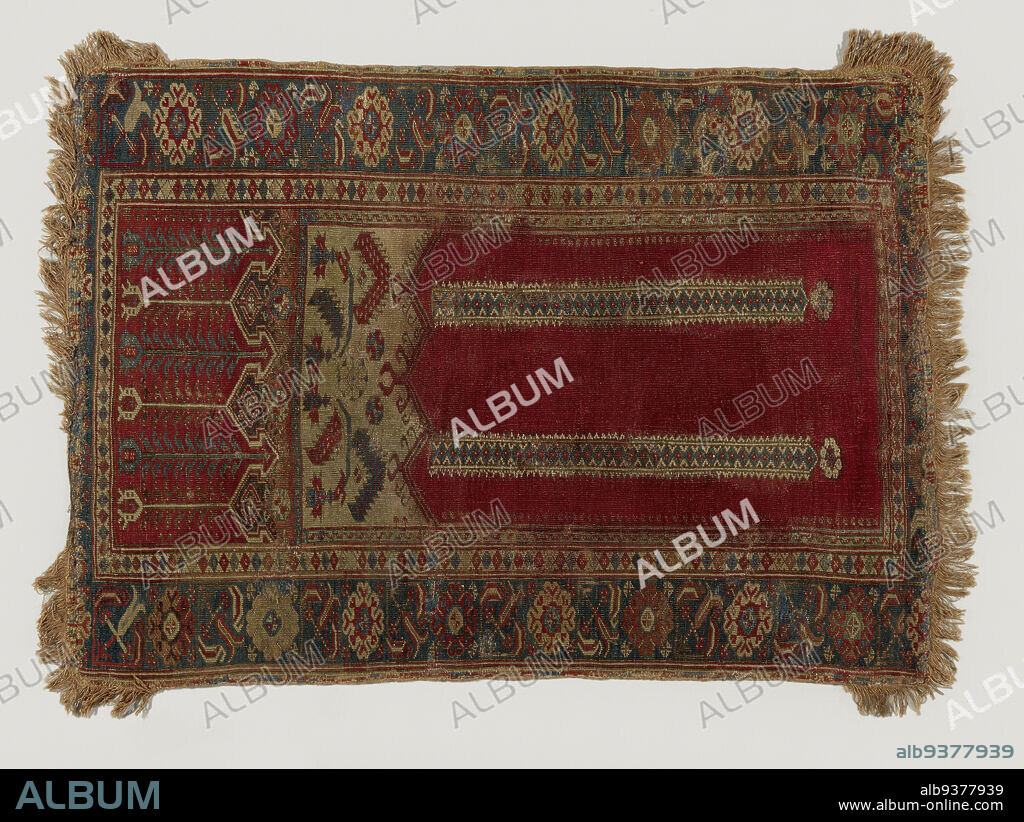 Prayer rug with upper warp panels, LADIK, Prayer rug with upper warp panels, LADIK. Midfield: stone-red mihrab with three equally high rectilinear gables, supported by two hovering columns. The white swags are raised with a pink transverse panel, with white/purple omega banding, transitioning to a red transverse panel with alternating blue and white tulips. Edges: triple. The main border is cobalt blue, on which are stocky diamond rosettes in red and white between oblique tulips in pink, red and white. Fringe: sewn-on, cotton fringe in pale pink-yellow, extending around the corners about 12 cm. at the side edges., Ladik, 1800 - 1850, wool, height 147 cm × width 105 cm.