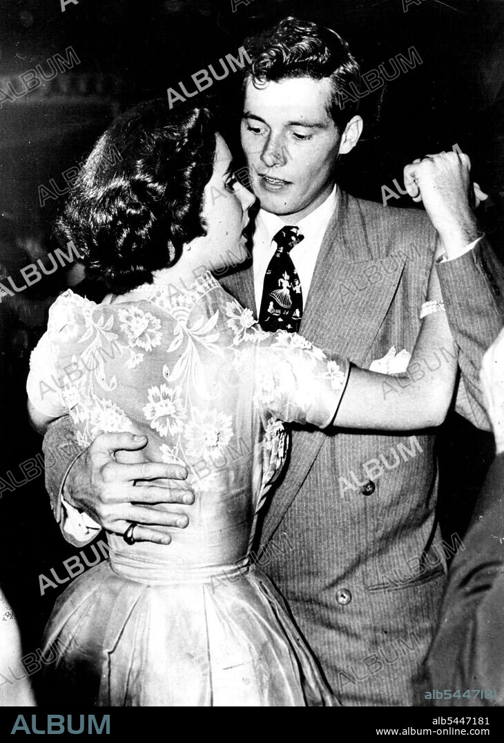 Hollywood Newly-Weds -- Keeping in step are film actress Elizabeth Taylor and her husband Conrad Hilton, Junior, ***** their "second honeymoon" by a visit ***** flower petals in relief. Her husband's gay tie caught the eye of dancers. June 5, 1950. (Photo by Paul Popper Ltd.).