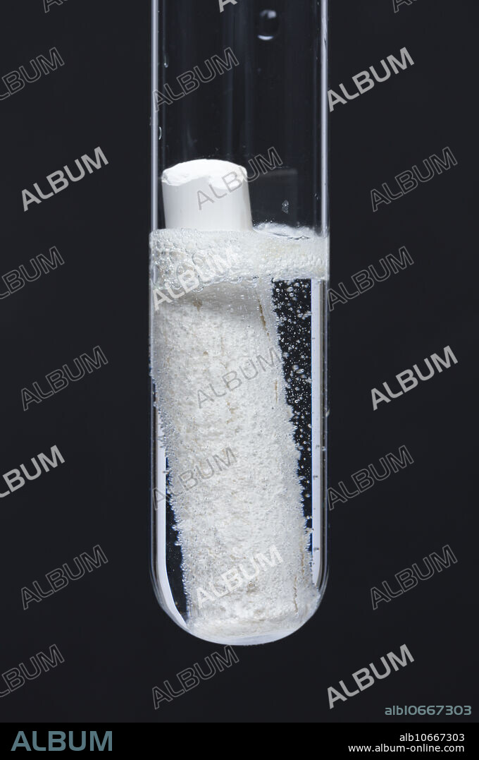 Chalk reacting with hydrochloric acid. Chalk (calcium carbonate, CaCO3) reacts with 0.5M hydrochloric acid (HCl) in a test tube. Carbon dioxide (CO2) bubbles are produced: CaCO3 + HCl -> CaCl2 + H2O + CO2.