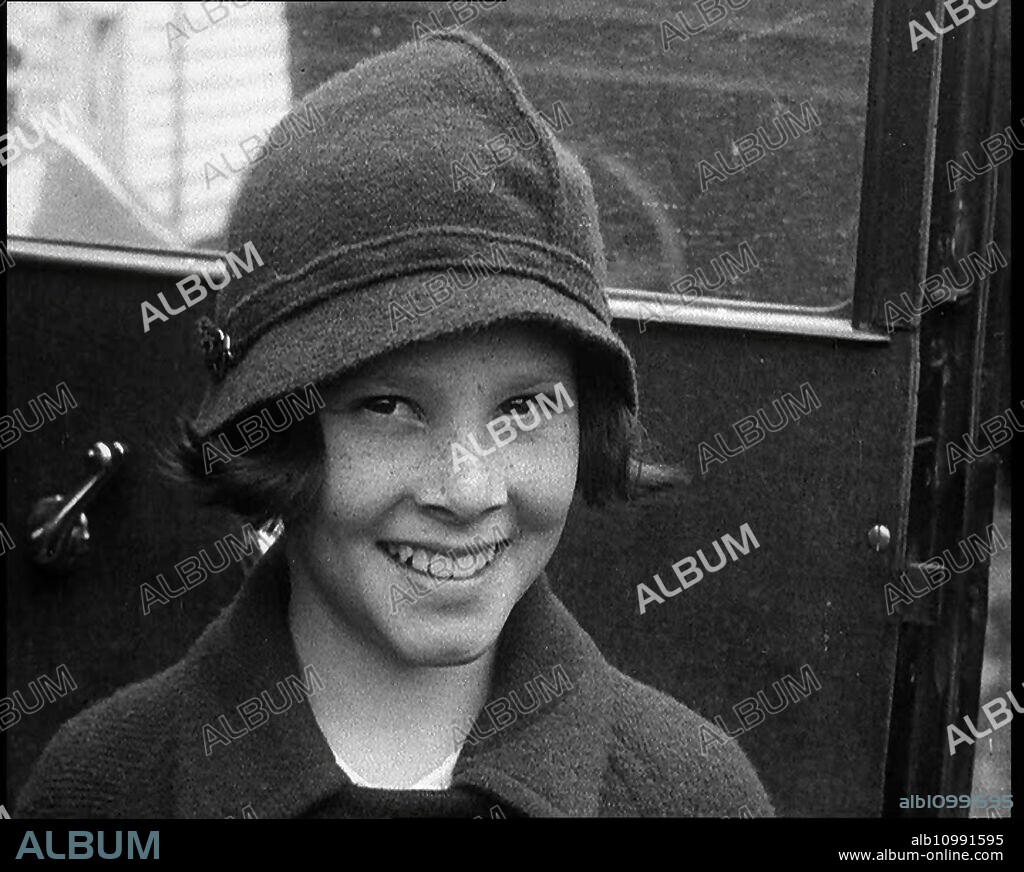 A Young Female American Civilian Being Rescued from Kidnapping Smiling at the Camera, 1930s. Wave of kidnappings: '...a small girl was kept prisoner. In this case the affair ended happily'. From "Time to Remember -  The Tough Guys", 1930s (Reel 1); a documentary film, mainly about life in depression- and gangster-hit America.