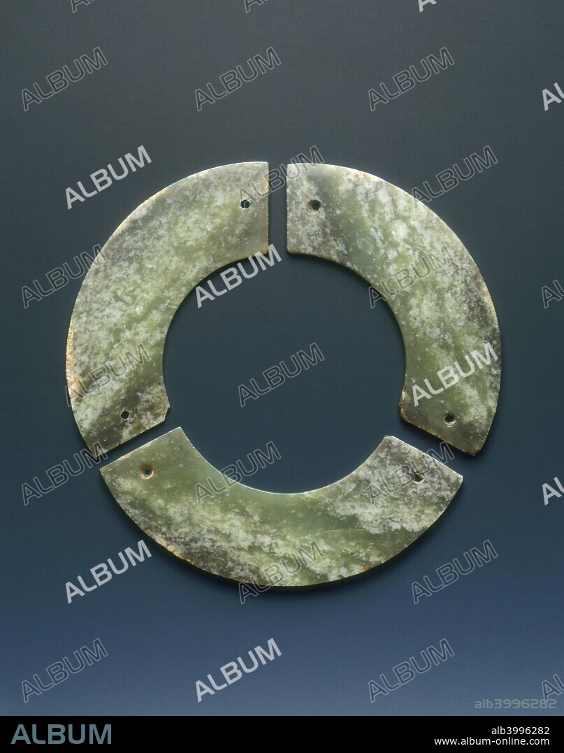Jade bi-disc made up of three huang segments, Shang dynasty, Anyang phase, China, c12th-9th century BC. A set of three jade huang segments making a complete circle. Each huang has a single hole at both ends all drilled from one side only. The jade pieces all come from one piece and have white flecks in each section.