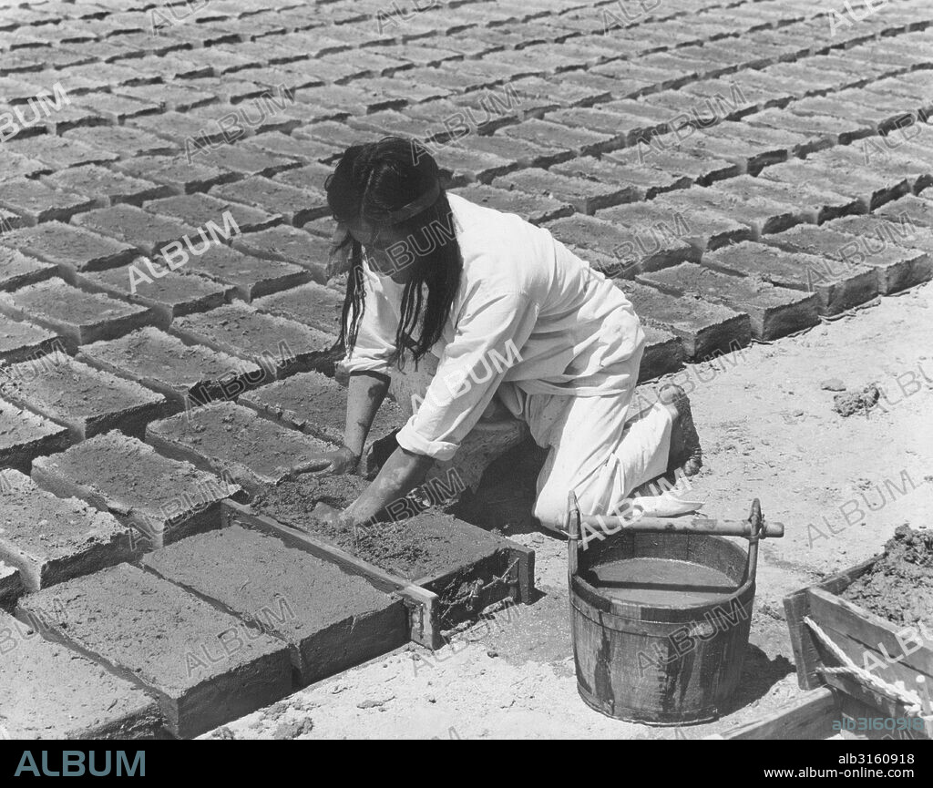 California: c. 1930 The padres taught the Native Americans to make the adobe bricks used in the building of the missions. The molder forces the adobe into all the corners of the mold by ramming his fist into the soft mud.