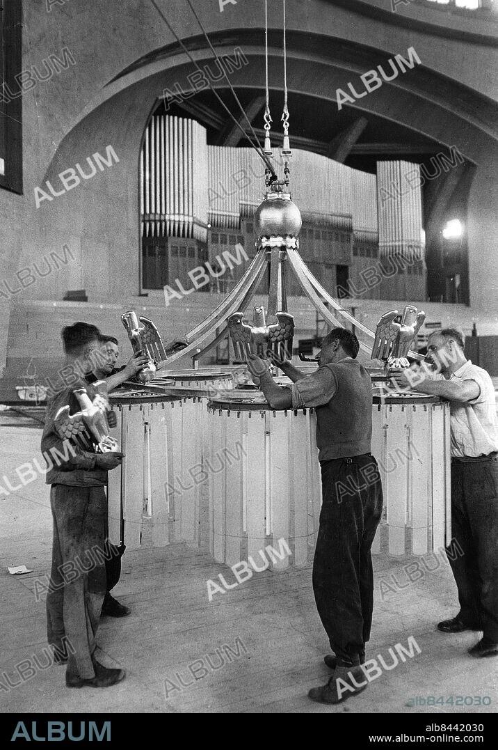 TYSKLAND BRESLAU 1937-07-22. Orig. bildtext... FÜR DAS 12. DEUTSCHE SÄNGERBUNDESFEST IN BRESLAU werden in Breslau die letzten Vorbereitungen getroffen. In der Jahrhunderthalle werden die Deckenlampen mit Hoheitszeichen geschmückt. Im Hintergrund die grosse Orgel. Foto: Scherl Bilderdienst / AB Text & Bilder / SVT / Kod: 5600 Mapp: Sångarfest i Breslau, Juli 1937 2118 B Orglar Symboler Den tyska örnen Statsvapen Musikfestivaler Körfestivaler Breslau - efter 1945 Wroclaw i Polen sites: TYSKLAND;BRESLAU.