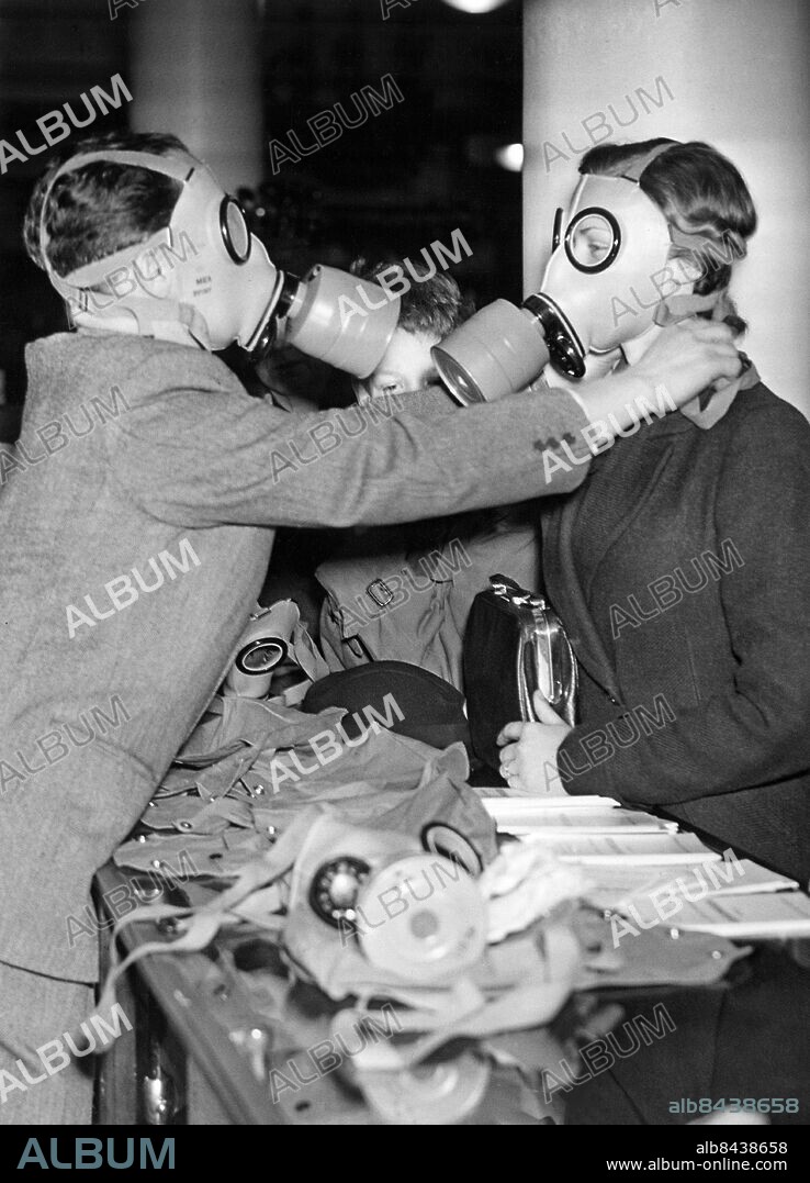STOCKHOLM 1938-03-08.. Orig. bildtext... DEN NYA FOLKGASMASKEN I MARKNADEN.. Folkgasmasken har nu kommit i marknaden och försäljningen började på tisdagsförmiddagen hos MEA i Stockholm. Denna gasmask, Fatra C, är den enda folkgasmask, som hittills godkänts av myndigheterna för civilbefolkningens skydd.. - Bilden visar: Ett biträde provar ut en gasmask på en kund.. Orig. bildtext... GAS MASKS FOR PUBLIC USE. today for the first time were sold in Stockholm. Photo shows th scene at the Military Equipment Shop this morning, when the first masks were sold.. Foto: AB Text & Bilder / SVT / Kod: 5600. Mapp: Civilförsvaret Sverige Gasskyddstjänst 4051G. Bildserier Fotoreportage.