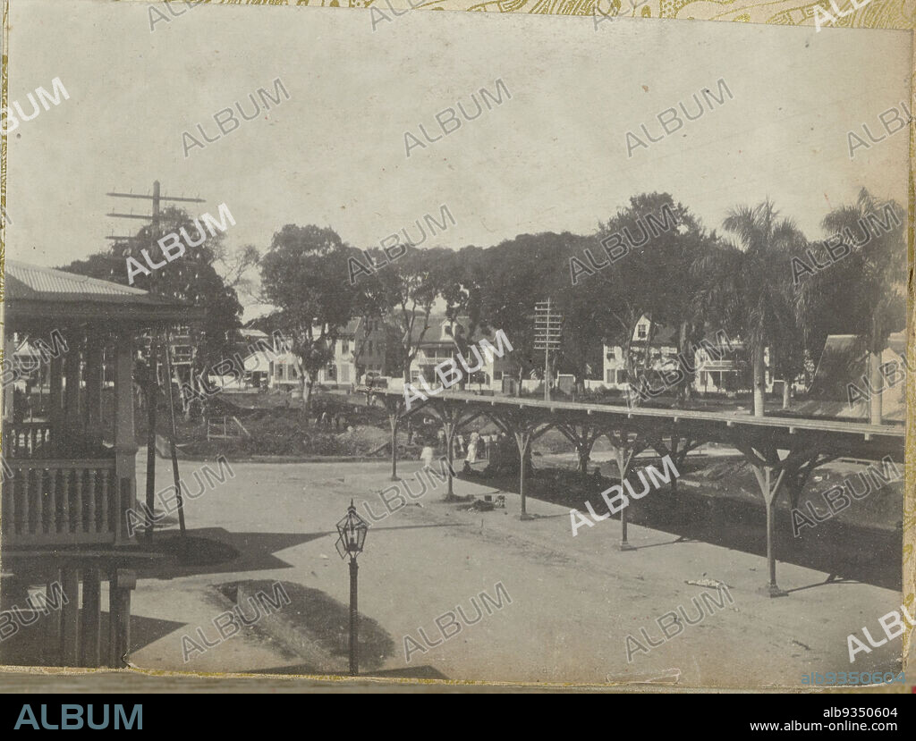 Heiligenweg and Vaillantsplein, Paramaribo, View of the Heiligenweg with covered passage and the Vaillantsplein in Paramaribo. Part of the photo album Souvenir de Voyage (part 1), about the life of the Doijer family in and around the plantation Ma Retraite in Suriname in the years 1906-1913., Hendrik Doijer (attributed to), Suriname, 1906 - 1913, photographic support, gelatin silver print, height 80 mm × width 109 mm.