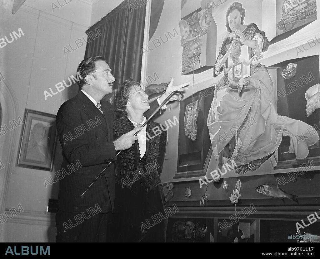 Salvador Dali discusses with his wife Gala his painting The Madonna of Port Lligat, at the opening of an exhibition of his work. 40 of Dali's works on display at an exhibition at the Leferve Galleries in Bruton Street, London. 2 December 1951.