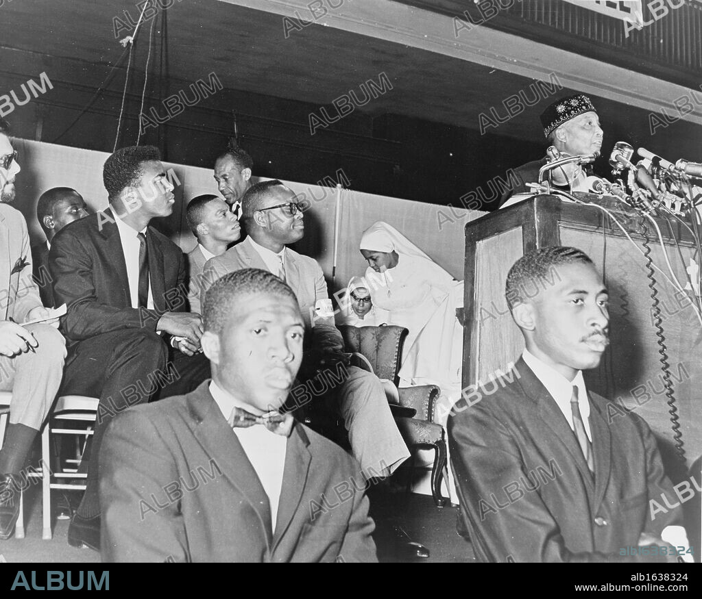 Elijah Muhammad (1897-1975, born Elijah Poole). Converted to Islam in 1931, from 1934 until his death be was leader of the Nation of  Islam. Here in 1964 addressing followers including Cassius Clay (Muhammad Ali).