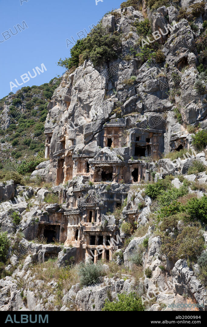 Turkey, Myra, Lycian Tombs. The large number of rock-cut tombs is strewn all across the cliff face in an asymmetrical pattern. Some are house-type tombs, while others are temple-like tombs. Most of the tombs were carved in the 4th century BC, many of which feature funerary scenes in relief, or scenes from the deceased person's daily life.