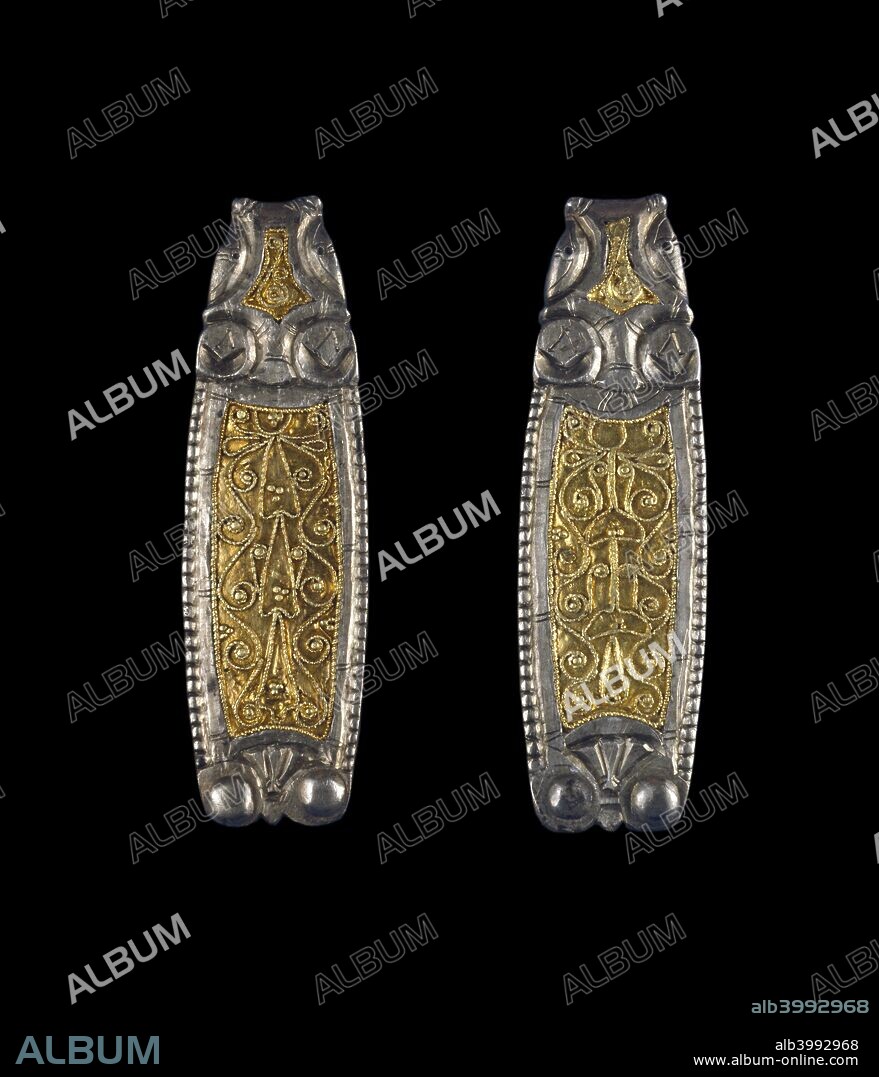Late-Saxon strap end, 9th century. The solid silver base has a sunken field covering most of the surfaces, into which is inlaid a sheet-gold panel decorated with symmetrical plant-scroll ornament in twisted filigree wire, punctuated by granules in gold. Dimensions: length: 5.7 cm.