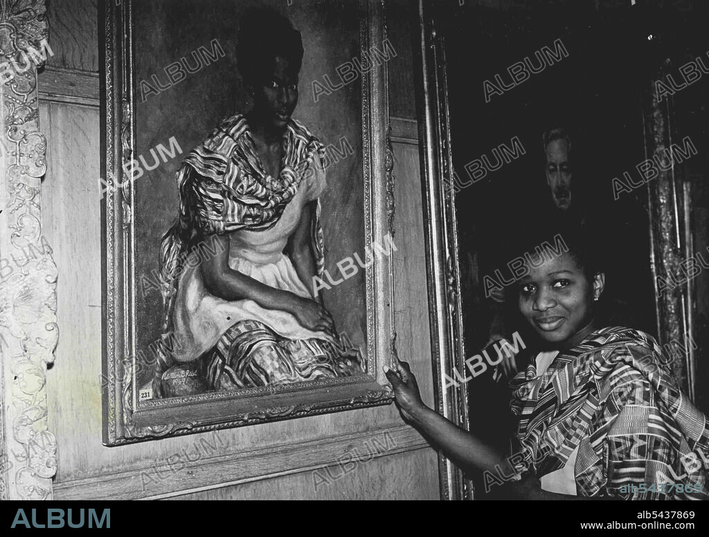 Hopes Father Will Buy Her Picture -- Frances Quashie-Idun, 21, brought a gay West African costume to wear at parties and dances when she came to Britain from her home at Accra, Gold Coast. But for most of the time she has worn the costume she has been sitting quite still while artist William E. Reid painted her. The portrait is hanging in the Piccadilly, London, exhibition of the Royal society of Portrait painters. Frances, studying English at University College, Oxford, hopes her father a Gold.
