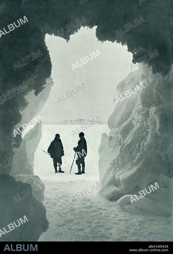 'An Ice Grotto - Tent Island in Distance (Captain Scott and Wright)', c1911, (1913). British Antarctic explorer and expedition leader Captain Robert Falcon Scott (1868-1912) with physicist Charles Seymour Wright (1887-1975). Scott's final expedition left London on 1 June 1910 bound for the South Pole. The Terra Nova Expedition, officially the British Antarctic Expedition (1910-1913), included a geologist, a zoologist, a surgeon, a photographer, an engineer, a ski expert, a meteorologist and a physicist among others. Scott wished to continue the scientific work that he had begun when leading the Discovery Expedition to the Antarctic in 1901-04. He also wanted to be the first to reach the geographic South Pole. Scott, accompanied by Dr Edward Wilson, Captain Lawrence Oates, Lieutenant Henry Bowers and Petty Officer Edgar Evans, reached the Pole on 17 January 1912, only to find that the Norwegian expedition under Amundsen had beaten them to their objective by a month. Delayed by blizzards, and running out of supplies, Scott and the remainder of his team died at the end of March. Their bodies and diaries were found eight months later. From Scott's Last Expedition, Volume I. [Smith, Elder & Co., London, 1913].