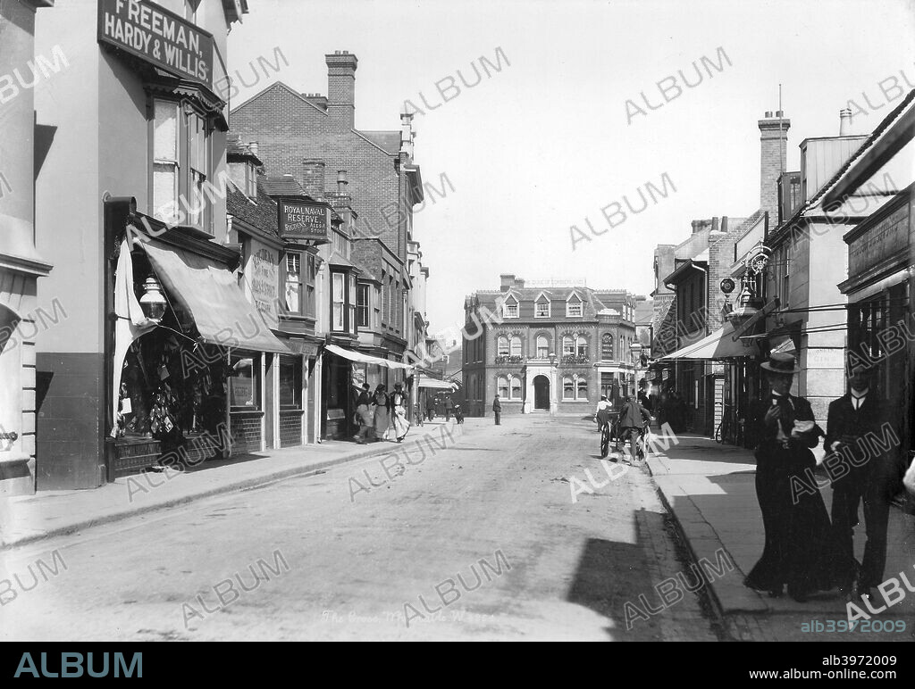High Street, Whitstable, Kent, 1890-1910. A view down the High Street on a windy day with pedestrians walking past the shops and public houses.