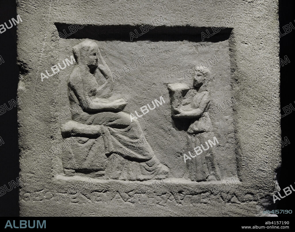 Stele of Theogeneta. Funerary stele of Hellenistic period. From a Greek city in Asia Minor, it features the funerary scene in bas-relief. The deceased is depicted sitting on a seat with a cushion, turning her attention to a smaller female figure, possibly a servant, who offers her a kalathos (basket in which women kept wool flakes for spinning). 3rd century BC. Marble. Detail. National Archaeological Museum. Madrid. Spain.
