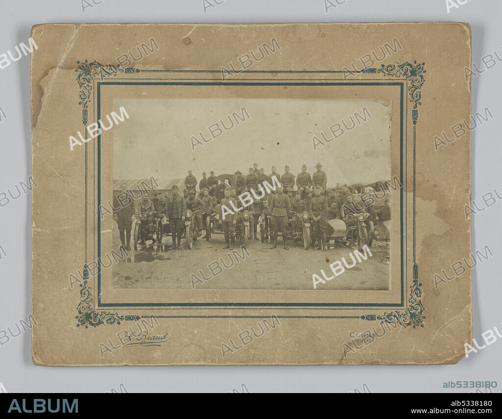 L. BIAUD. A black-and-white photographic print on a cardboard mount depicting a group of soldiers of the American Expeditionary Forces serving in France during World War I. Some of the soldiers are sitting on motorcycles. Buildings and vehicles can be seen behind the soldiers. The print is pasted on a card mount with a printed decorative frame around the opening. The photographer's name is printed in the lower left corner and the place of the studio is printed in the lower right corner. Handwritten in graphite on the reverse is the text "2119 G Hamilton".