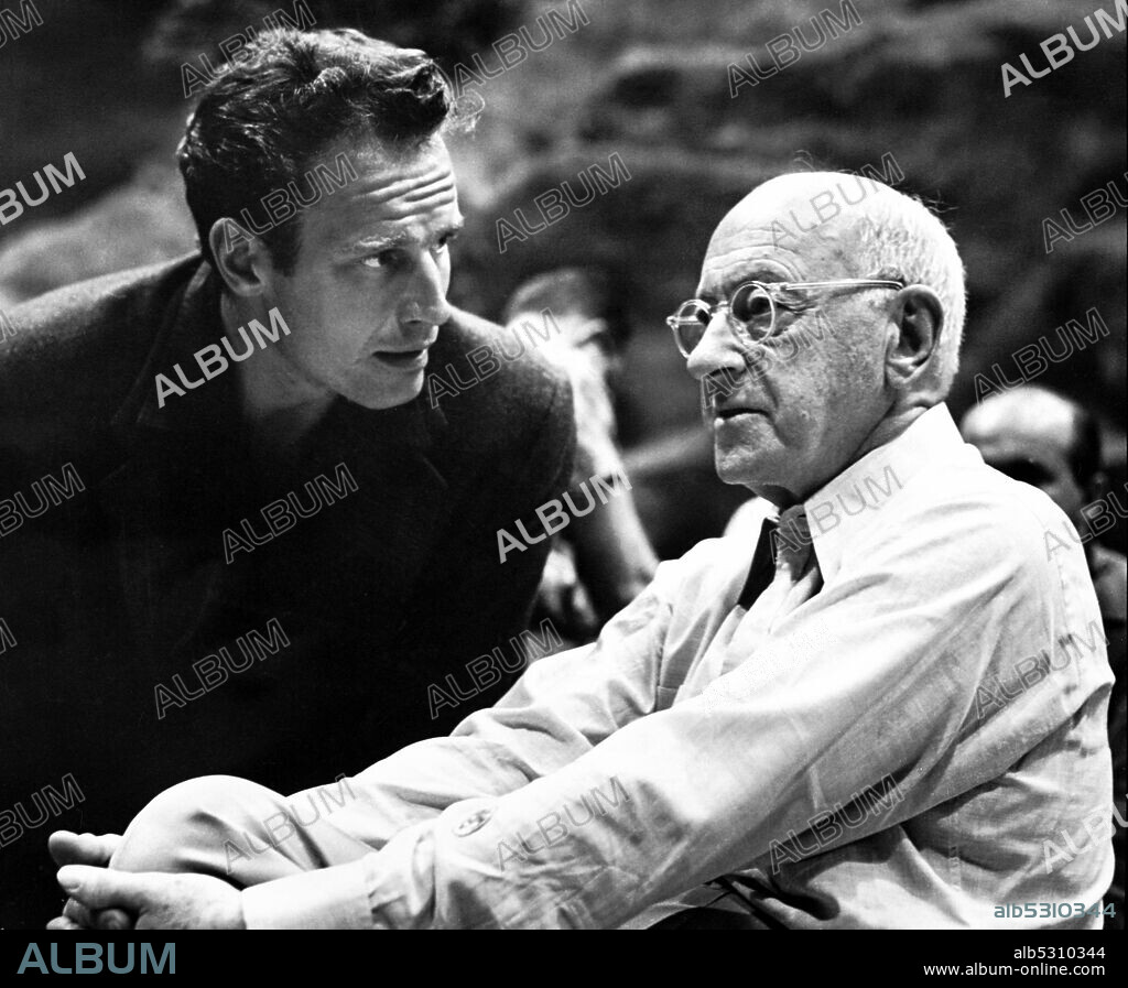 CECIL B DEMILLE and CHARLTON HESTON in THE TEN COMMANDMENTS, 1956, directed by CECIL B DEMILLE. Copyright ZUMA Wire. 1955, Hollywood, California, USA: American actor CHARLTON HESTON gets direction from CECILLE B. DEMILLE on set of the film 'The Ten Commandments.' The Ten Commandments dramatizes the biblical story of the life of Moses, an adopted Egyptian prince who becomes the deliverer of his real brethren, the enslaved Hebrews, and thereafter leads the Exodus to Mount Sinai, where he receives, from God, the Ten Commandments.