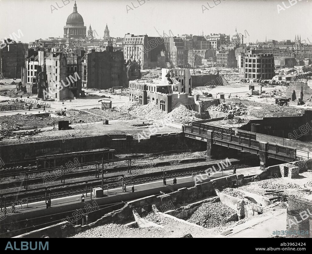 The Barbican area of the City of London, World War II, 1942. View showing the devastation following the demolition of unsafe buildings damaged by German bombing. Amongst the rubble people can be seen standing on the station platform waiting to catch a train.