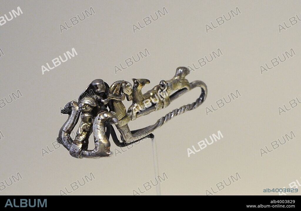 Cultura Ibérica. Fíbula tipo La Tène II. Era el distintivo de un équites. Se representa una escena de caza y, entre dos prótomos de caballo, a la Diosa Potnia Theron. Siglo II a. C. Plata sobredorada. Procedente de Cañete de las Torres (provincia de Córdoba). Museo Arqueológico Nacional. Madrid. España.