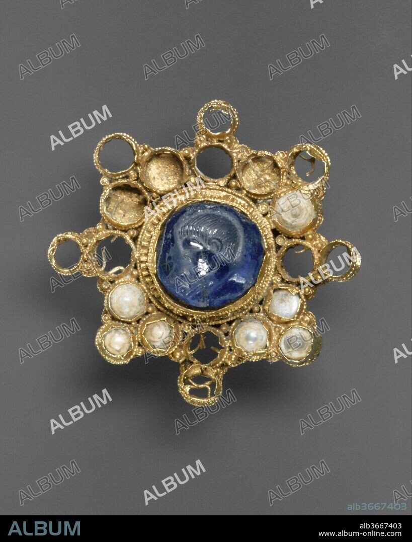 Star-Shaped Brooch with Intaglio. Culture: Ottonian (Rhineland (?)) (setting); Byzantine (intaglio). Dimensions: Overall: Diam. 4 11/16 x 3/4 in. (Diam.11.9 x 1.9 cm). Date: ca. 950-1000 (setting); 337-50 (intaglio).
Jewels conveived as microarchitecure are one of the distinctive hallmarks of Ottonian goldsmiths' work. This brooch is compopsed of a series of arcaded gold cells, linked together to form a star, but its definite horizontal and vertical axes, in fact, make it cross shaped. Because the brooch was buried some gems are missing. Although most of the spaces between the arms of the cross still contain pearls, the arms themselves probably would have been set with amethysts. Raised above the arcaded cluster is an arcaded rotunda that supports a large star-sapphire intaglio.