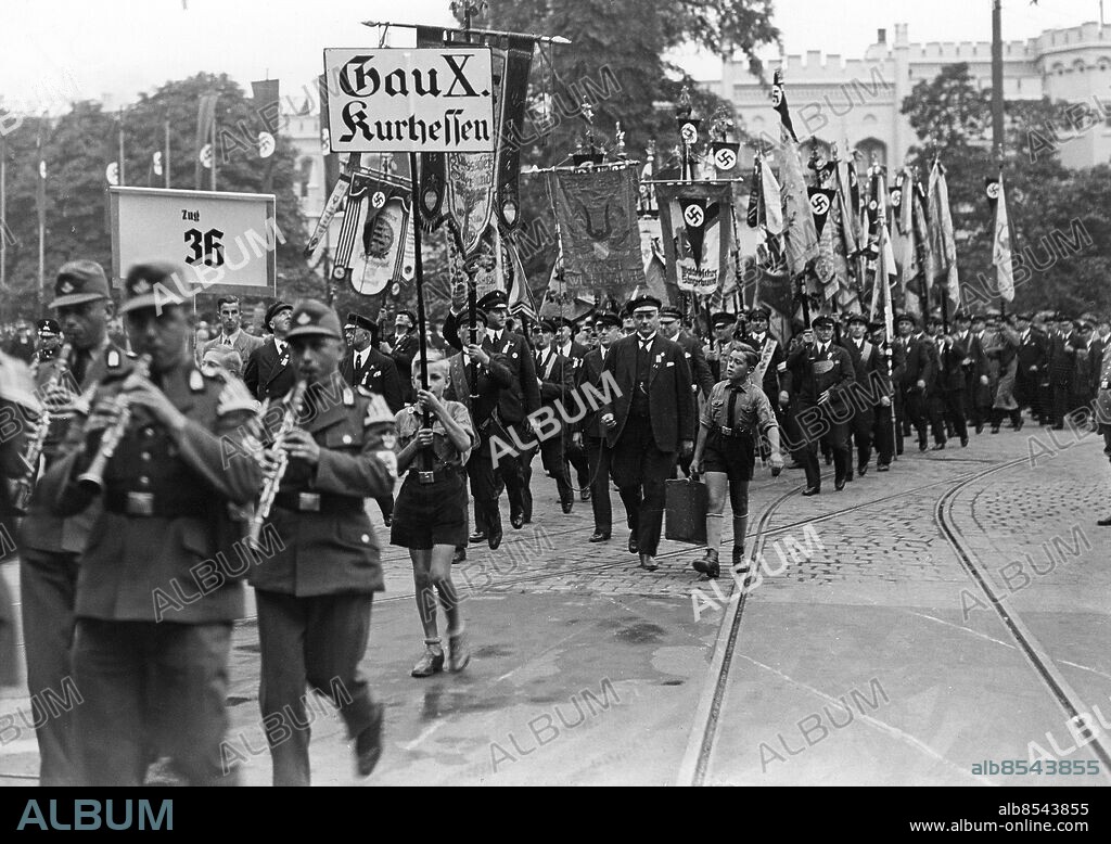TYSKLAND BRESLAU 1937-07-29. Orig. bildtext... 12. DEUTSCHES SÄNGERBUNDESFEST. Das Hauptereignis des Donnerstag bildet die feierliche Fahnenübergabe des Sängerbundesbanners auf dem Schlosspaltz an die Stadt Breslau. Schon in den ersten Morgenstunden begaben sich Züge der auswärtigen Sänger mit ihren Bannern und Fahnen zu der Feierstunde auf dem Schlossplatz. Auf unserem bild marschiert die Fahnengruppe des Gaues X Kurhessen unter Vorantritt eiener Arbeitsdienstkapelle zum Schlossplatz. Foto: Scherl Bilderdienst / AB Text & Bilder / SVT / Kod: 5600 Mapp: Sångarfest i Breslau, Juli 1937 2118 B Hakkors Fanor Standar Musikfestivaler Körfestivaler Breslau - efter 1945 Wroclaw i Polen sites: TYSKLAND;BRESLAU.
