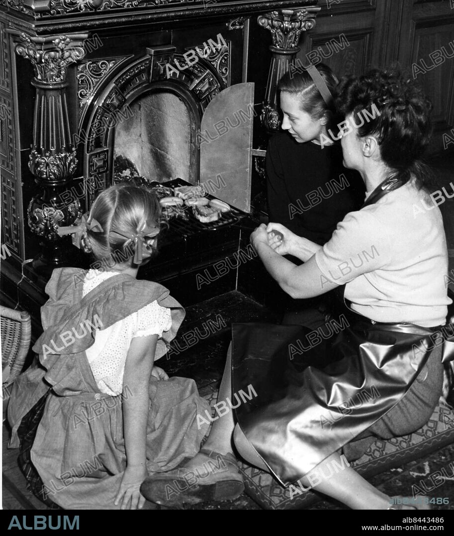 Arkiv 1951. Gunila Stierngranat-Lind vid öppna spisen tillsammans med döttrarna Lotti och Christina. Stierngranat-Lind var känd som tecknare.. Foto: Arne Schweitz Kod:1049. Scanpix Sweden.