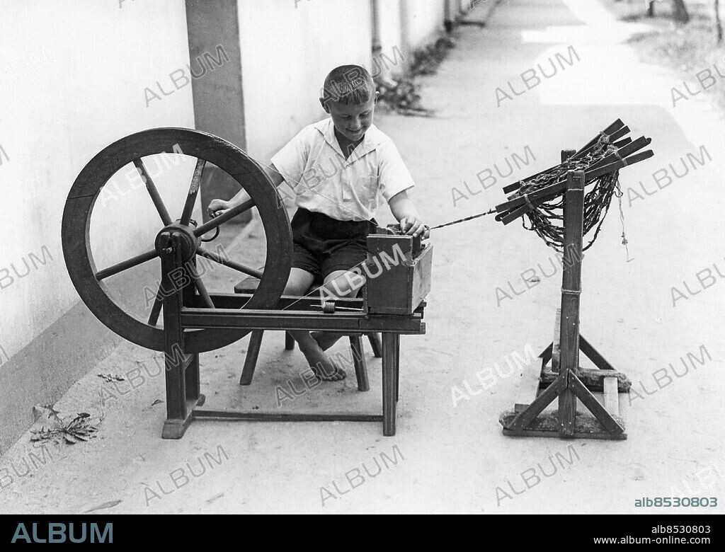 TYSKLAND JÜTERBOG omkring 1930. Orig. bildtext... HANDWEBEREI KOMMT WIEDER ZU EHREN. Bei den Handweberei in Kloster Zinna b/Jüterbog. (Mark). 40061) Alles hilft: Flinke Kinderhände an der Spule. Foto: Robert Sennecke / AB Text & Bilder / SVT / Kod: 5600 Mapp: Handarbete Spinning Diverse länder 4914 B Bildserier Fotoreportage Spinnrockar sites: JÜTERBOG;TYSKLAND PhotoDate:193?-??-??.