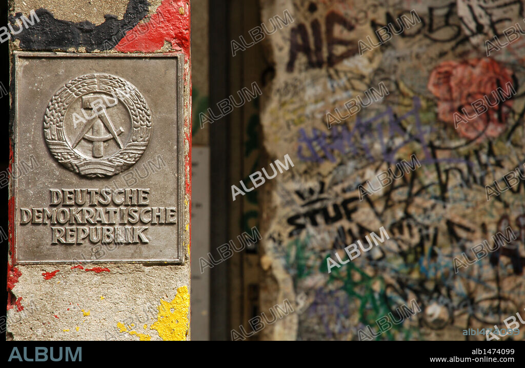 Símbolo de la antigua R. D. A. (República Democrática Alemana) junto a un tramo del MURO DE BERLIN, en el "Haus AM Checkpoint Charlie". BERLIN. Alemania.