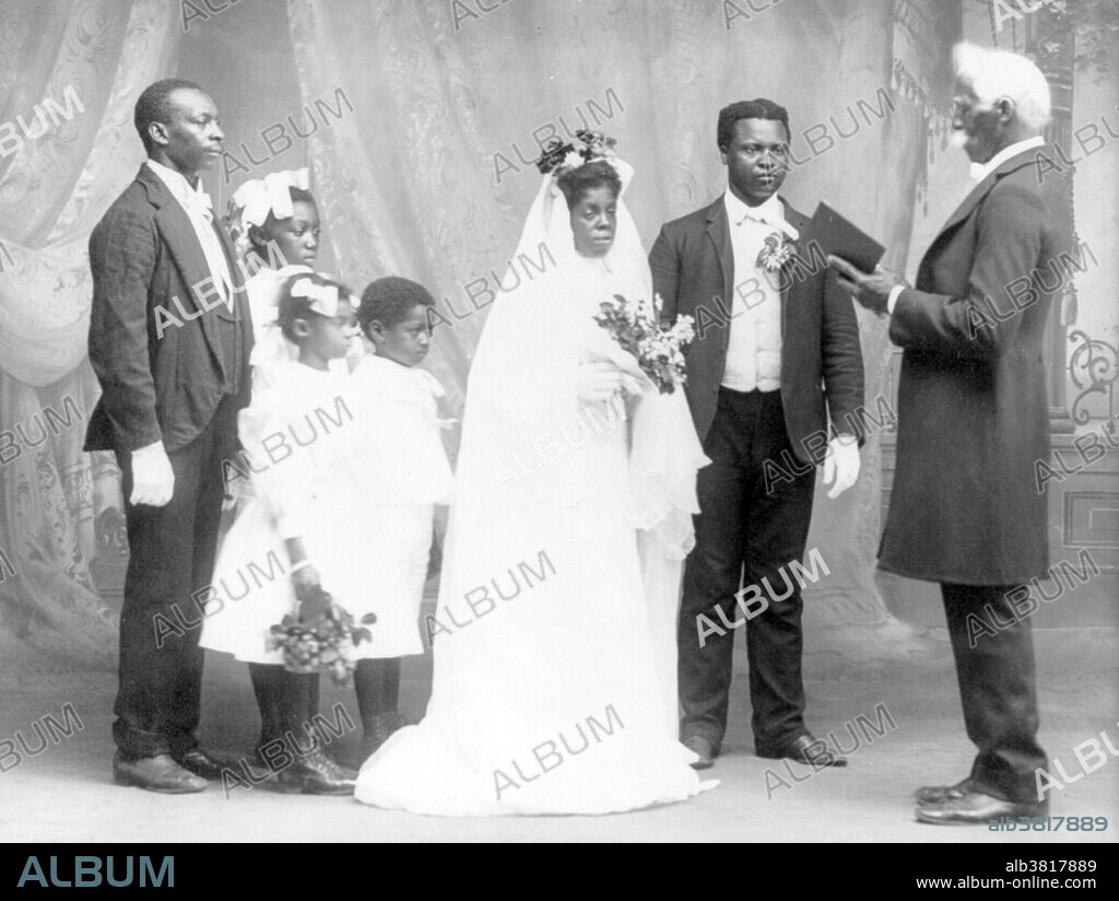 Entitled: "She was led to the Altar" shows an African-American wedding showing bride and groom, preacher, three children and one other man. Wedding traditions and customs vary greatly between cultures, ethnic groups, religions, countries, and social classes. Most wedding ceremonies involve an exchange of wedding vows by the couple and a public proclamation of marriage by an authority figure or leader. A number of cultures have adopted the traditional Western custom of the white wedding, in which a bride wears a white wedding dress and veil. The use of a wedding ring has long been part of religious weddings in Europe and America, but the origin of the tradition is unclear. The wedding ceremony is often followed by a drinks reception then a wedding breakfast, in which the rituals may include speeches from the groom, best man, father of the bride and possibly the bride, the newlyweds first dance as a couple, and the cutting of an elegant wedding cake. Photographed by Mary Elizabeth Wheeler March 9, 1908.