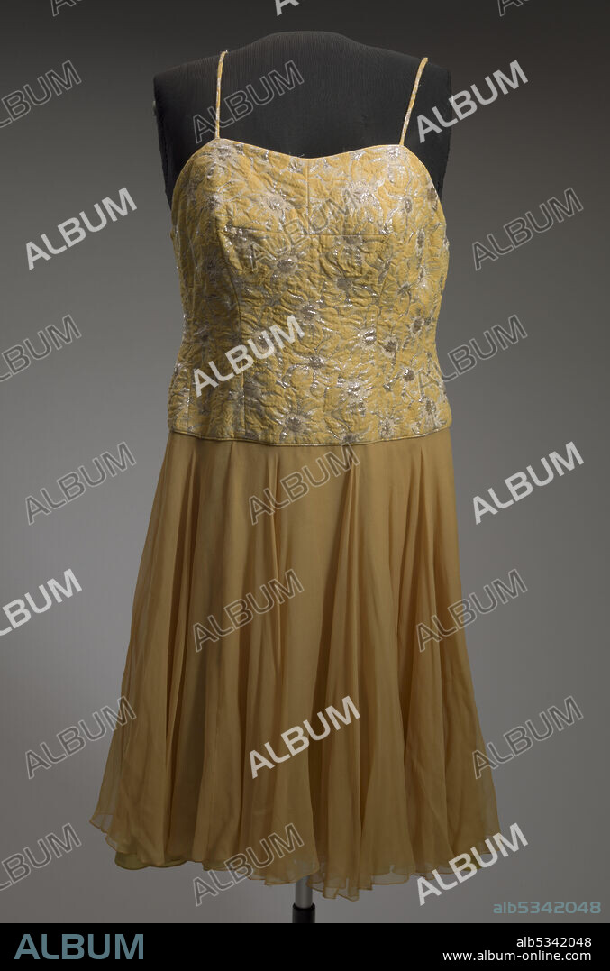 This yellow and orange cocktail dress was designed by Don Loper and worn by African-American jazz singer Ella Fitzgerald. The bodice of the dress is fitted with a sweetheart neckline and spaghetti straps. It is made from a yellow, white, and silver metallic woven floral design. The bodice ends at the hip with a knee-length circle skirt below it. The skirt is made from two layers of marigold colored silk chiffon with an underskirt made from a chartreuse synthetic fabric.