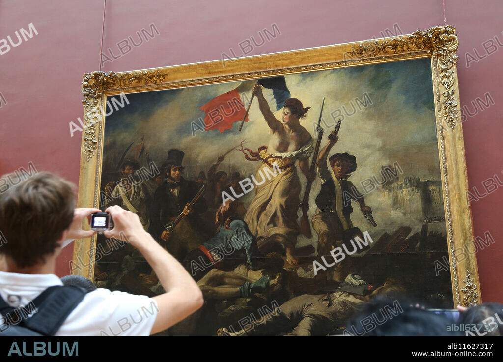Tourist inside Louvre Museum.  Liberty leading the people, 1831. By Eugene Delacroix. Paris.