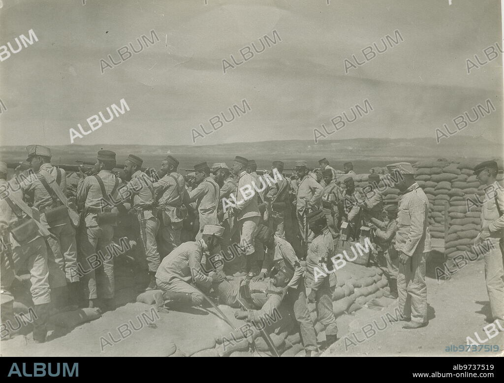 Morocco. 1909. The Riff Offensive. Spanish soldiers attacked from a blockhouse. In the foreground, a wounded soldier is carried by his comrades.