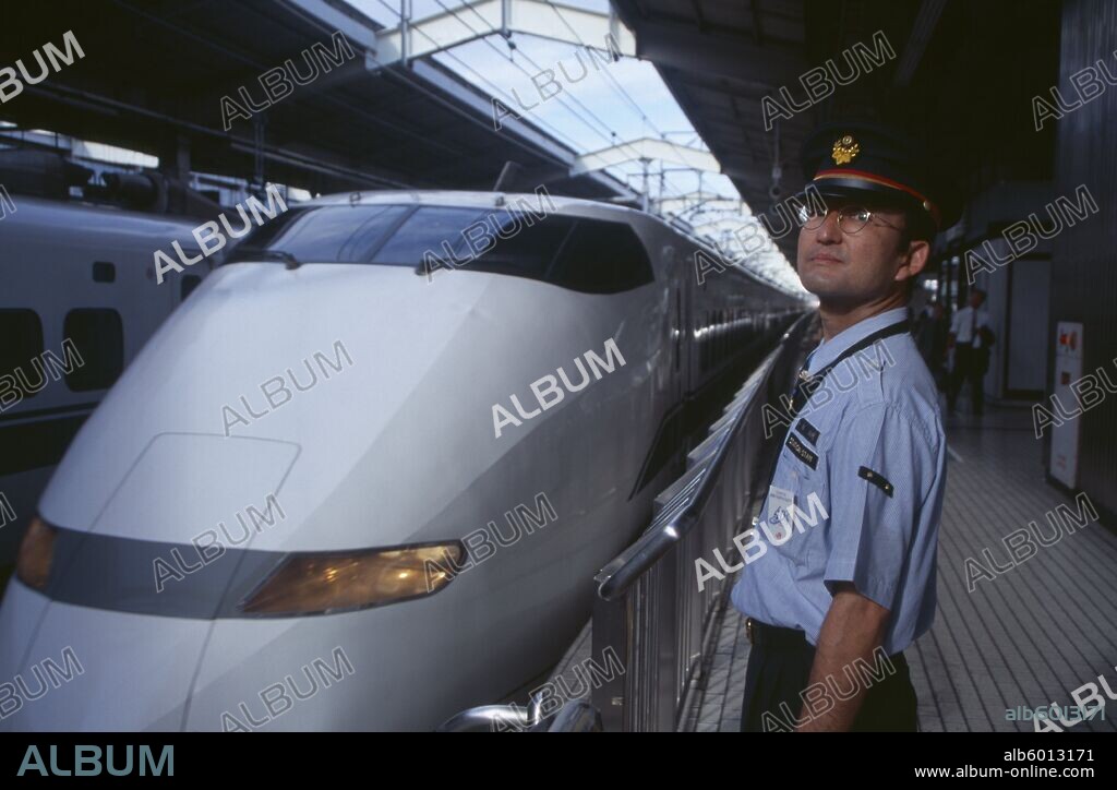 JAPAN Honshu Kyoto Bullet train aka Shinkansen pulling into the station platform with train guard standing in the foreground.