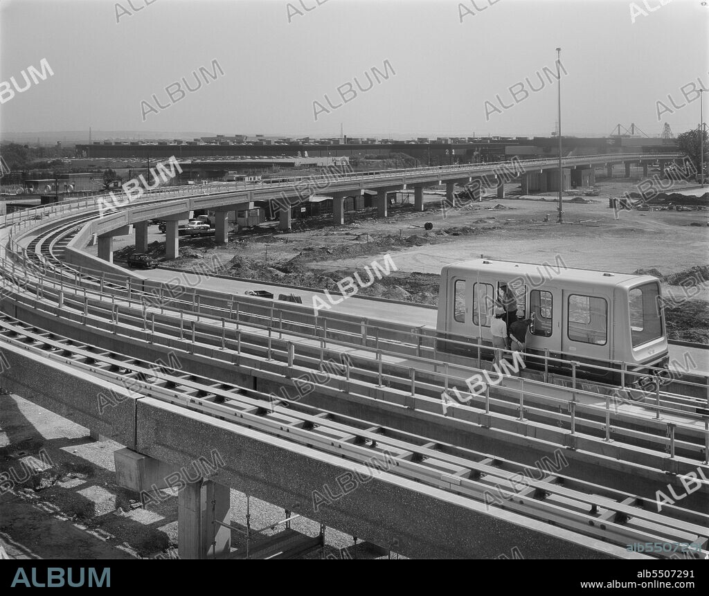 Birmingham Airport, Birmingham Maglev, Elmdon, Birmingham, Bickenhill, Solihull, 15/08/1983. Workmen inspecting a new Maglev car on the new Maglev system at Birmingham Airport near the end of its construction, with Birmingham International railway station beyond. The Maglev system at Birmingham Airport was the first commercial Maglev system in the world. It used frictionless magnetic suspension to drive passenger cars along an elevated guideway between the airport terminal and Birmingham International railway station. Three cars were installed, and each could transport up to 32 passengers and their luggage along the 620 metres of track in 1 minute 30 seconds. The Birmingham Maglev was opened in 1984.