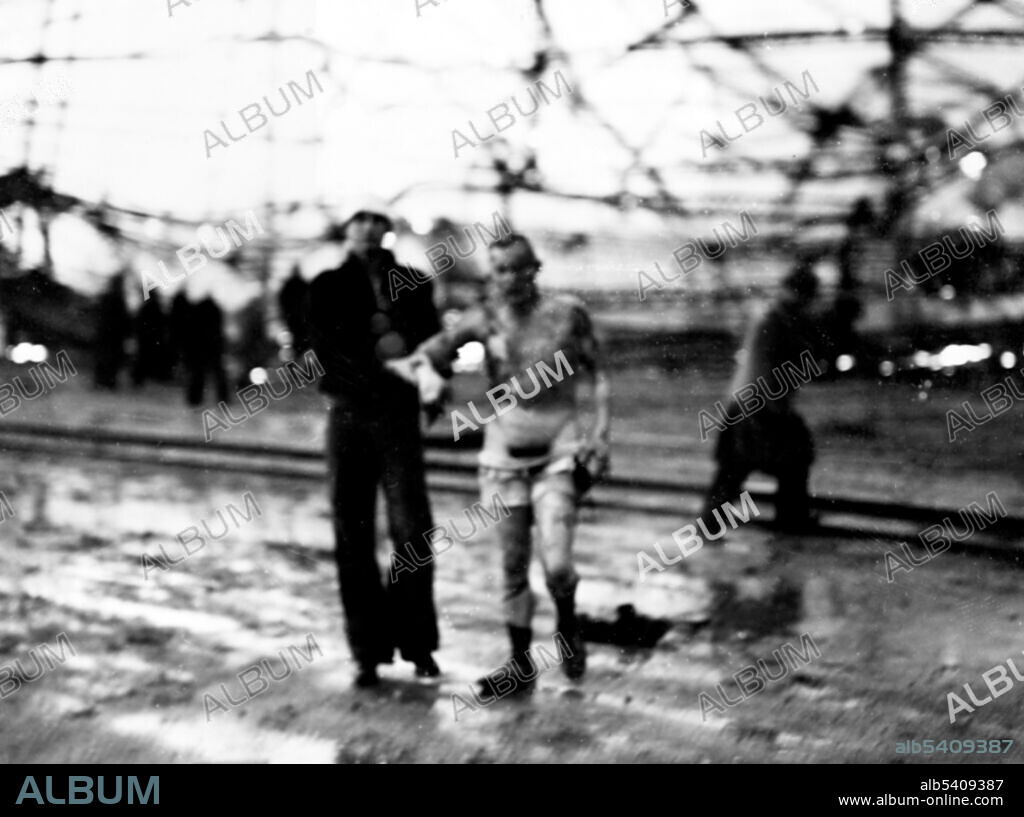 A sailor helps a survivor from the wreckage of the German Airship Hindenberg. The Hindenburg disaster took place on Thursday, May 6, 1937, as the German passenger airship LZ 129 Hindenburg caught fire and was destroyed during its attempt to dock with its mooring mast at the Lakehurst Naval Air Station, which is located adjacent to the borough of Lakehurst, New Jersey. Of the 97 people on board there were 35 fatalities as well as one death among the ground crew. The cause of the fire remains unknown. The incident shattered public confidence in the giant, passenger-carrying rigid airship and marked the end of the airship era. International News Service (cropped and cleaned).