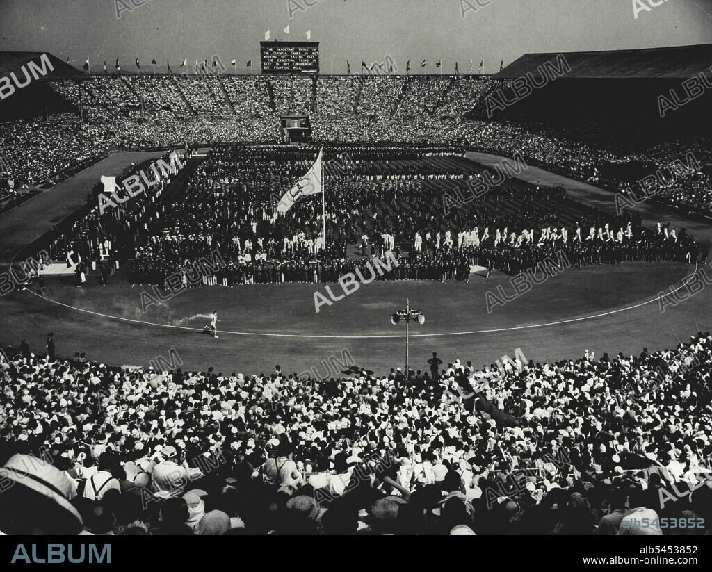 Olympic Flame Arrives At Wembley: The scene at Wembley Stadium, London, this afternoon, July 29, as Cambridge University Athlete John Mark carries the Olympic Flame on its final part of its journey from Greece. As he makes his circuit, six thousand Olympic competitors are massed in the centre of the crowded Arena. July 29, 1948. (Photo by Olympic Photo Association).