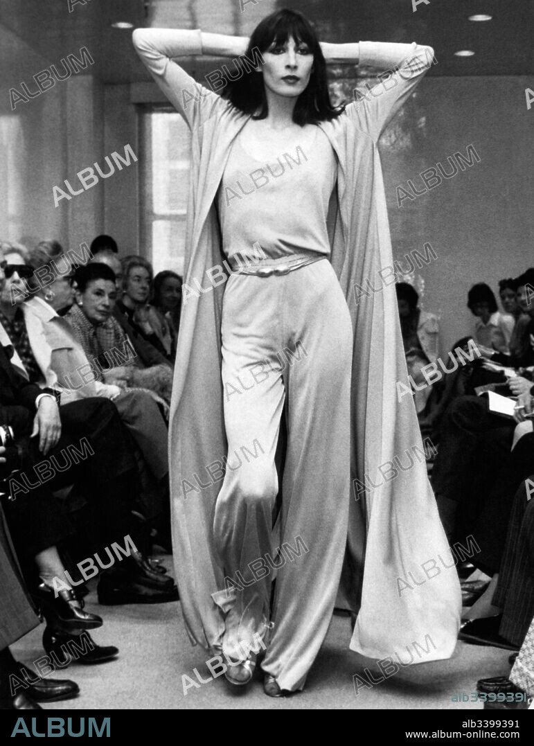 New York, New York: May 23, 1972 Angelica Huston models a Halston Originals jersey evening pants ensemble with a matching full coat.