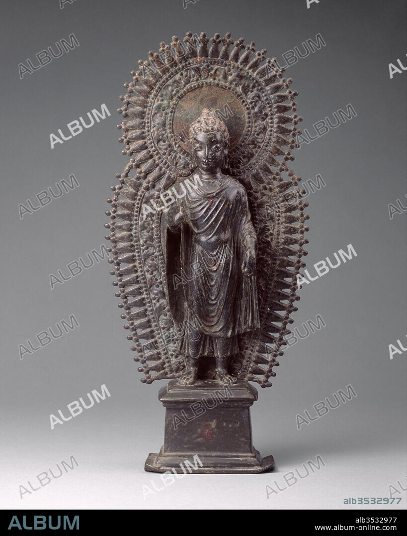 Standing Buddha with Radiate Combined Halo, ca. late 6th century, Pakistan (ancient region of Gandhara), Brass, H. 13 1/4 in. (33.7 cm), Sculpture, A few small personal images from Gandhara representing the Buddha have survived. This metal image blends elements seen in the stone sculpture of Gandhara with the Gupta style of north India. Its portability made it an important vehicle for disseminating the Gandharan style to other parts of Asia.