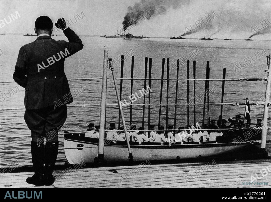 Adolf Hitler waving ships on parade. Fuhrer and Chancellor of Germany Adolf Hitler waving the ships on parade of the German Navy. Sailors in a lifeboat respond to the salute raising oars. Germany, June 1935.