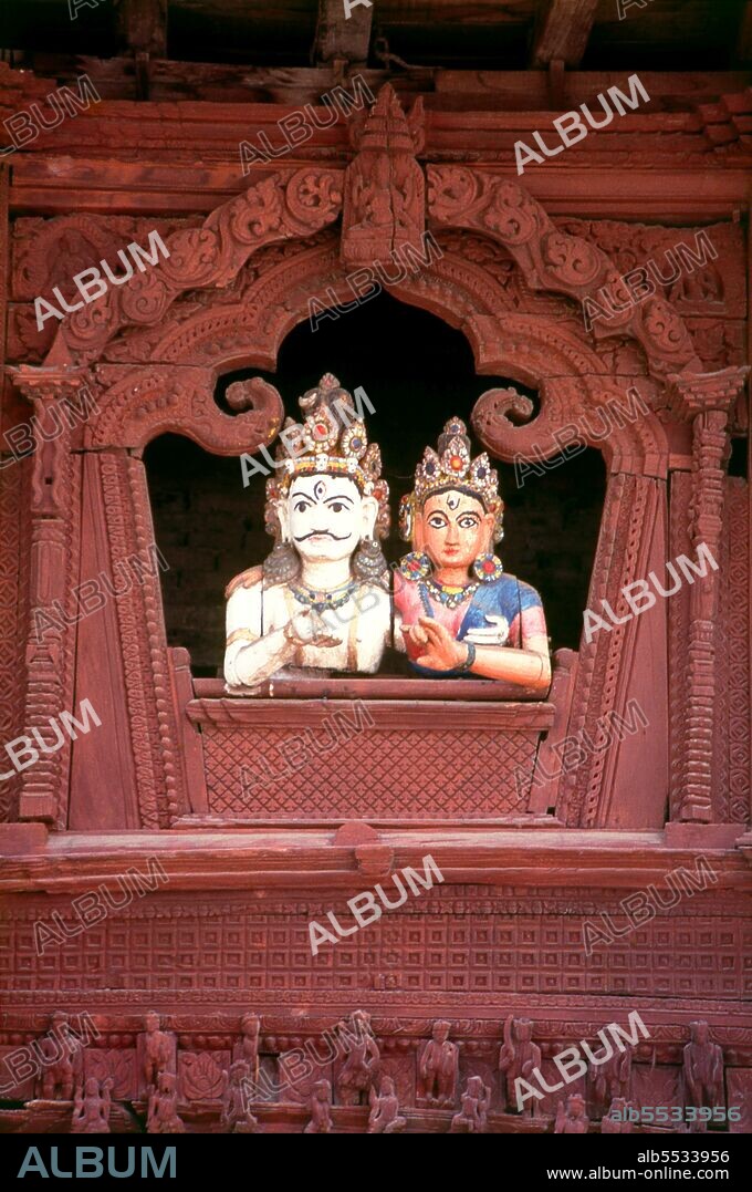 In the late 18th century CE, Rana Bahadur Shah, the grandson of Prithvi Narayan Shah, built a Shiva-Parvati Temple on Durbar Square, which was also, in a way, to become a monument to the joys—or vagaries—of married life. The temple, built on a platform formerly used for dance performances, is dedicated to the divine couple Shiva and Parvati. From an arched, carved window in its upper storey two wooden figures representing Shiva and Parvati look down on the square below. The figures are extraordinarily life-like, and from a distance one may almost be fooled. Their elbows casually rest on the windowsill, and the couple appears the very image of wedded bliss.