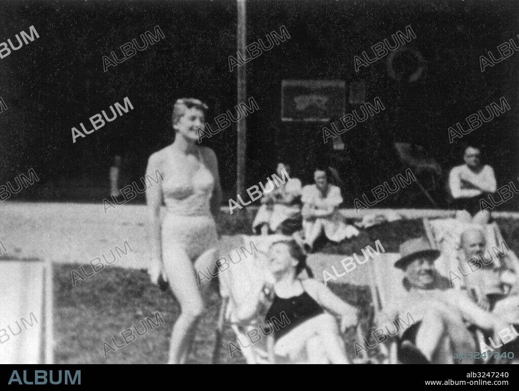 Orig. bildtext... SOMETHING NEW ON HITLER'S EVA Frankfurt, Germany. These photographs are from a recently discovered series of color films taken between 1938 and 1941 at Berchtesgaden, Hitler's eagle's nest retreat in the Bavarian alps, and other holiday resorts in Austria by Heinrich Hoffman, Hitler's private photographer. Eva Braun, the girl who is reported to have married Hitler during the last days of the siege of Berlin and who later died with him, according to accepted reports, makes many appearances in the series. She is shown here (top left) on the shore of the Wolfgangsee in Austria, at lower left, she exercises on the beach, top right, Eva (standing) with unidentified friends in Austria. Lower right, Grete Braun Fegelein, Eva's sister and wife of a nazi party boss, poses in the nude by a waterfall. 1-6-47 Anm. Se även XAE836 Semesterbilder tagna av Hitlers privata fotograf Heinrich Hoffmann. E Braun, 1912-1945, Adolf Hitlers älskarinna och senare hustru. Berchtesgaden - semesteranläggning, kallad Örnnästet, gåva till Adolf Hitler från det nationalsocialistiska partiet. Bildserier Fotoreportage Baddräkter Sola Solstolar Vänner CD588 persons: EVA BRAUN sites: TYSKLAND*;ÖSTERRIKE.