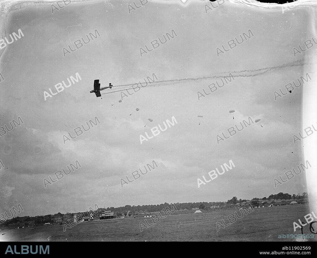 Parachute display in Hendon Pageant rehearsal. A full rehearsal of the Royal Air Force Pageant to be held at Hendon Aerodrome on Saturday took place at Hendon. Hundreds of Britain's latest aircraft are taking part in the display at which some of the newest methods of operation are being demonstrated. Photo shows, parachutes descending as a Vickers Virginia bomber is shot down in 'flames'. 24 June 1937.