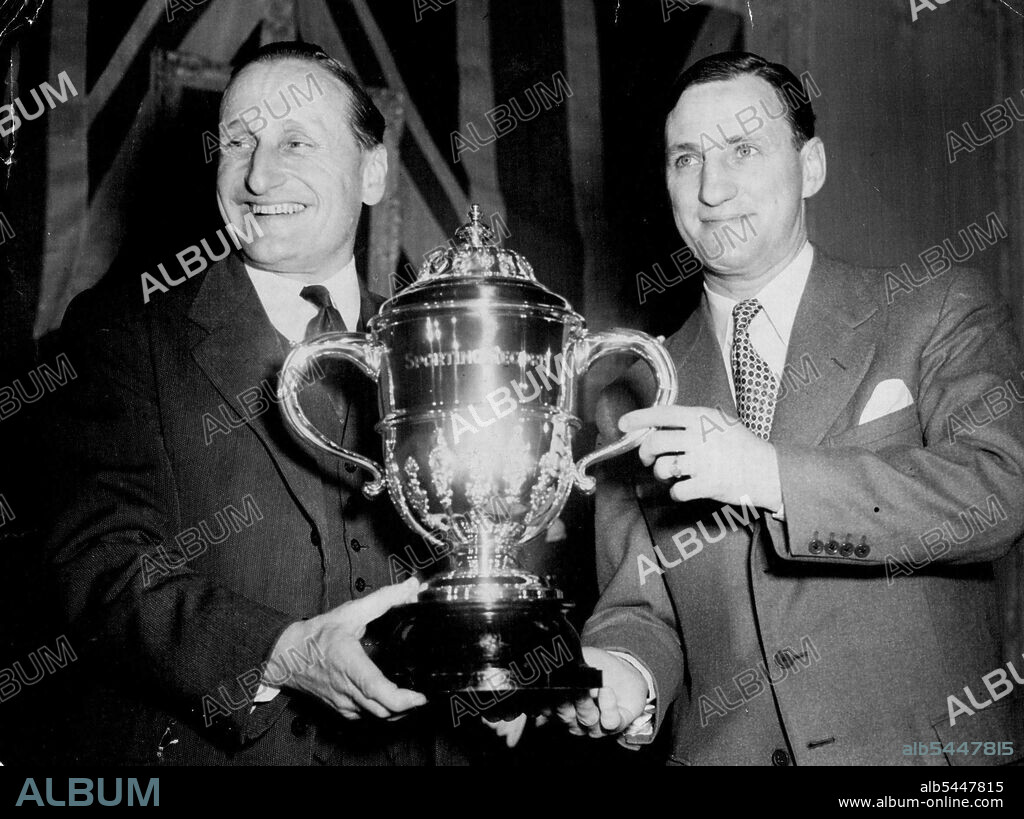 Len Hutton Receives Sportsman Of The Year Trophy -- Man who has batted his way to the top, Len Hutton, of Yorkshire, England's first professional cricket captain, is seen receiving from Lord Broughley left, at London's Savoy Hotel tonight (Monday) the 'Sportsman of the year' trophy awarded to him in the seventh annual national ballet organised by the 'Sporting Record'. Len Hutton is famous as one of the best opening batmen in the world. In the 1952 cricket averages he was shown to have scored 2567 runs in 45 innings. His highest innings score was 189. He made eleven centuries during the season and his average score was 61.11. March 23, 1953. (Photo by Reuterphoto).