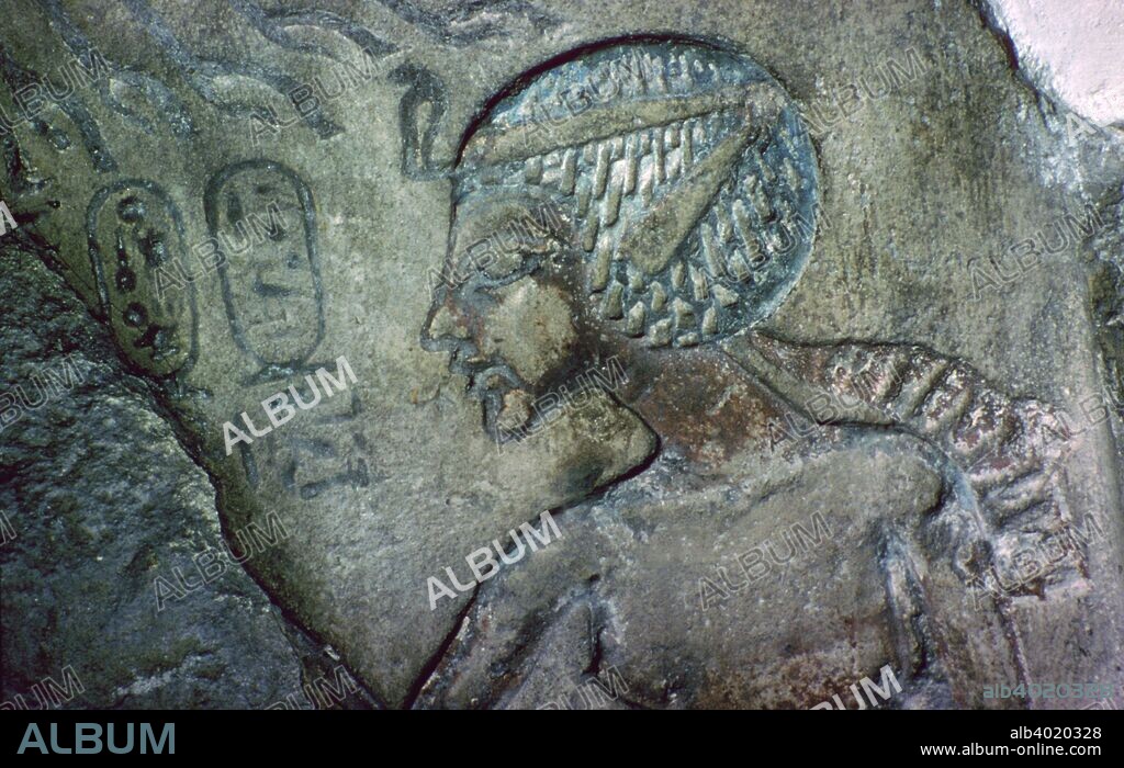 Detail of limestone stela with a seated figure of Akhenaten, probably from Amarna, Egypt, 18th Dynasty, c1340 BC. This limestone stela illustrates the shift in religious beliefs and artistic syle during the Amarna Period. The king, Amenhotep IV (Akhenaten, reigned 1390-1352 BC), is shown in a relaxed pose, which would have been unthinkable in earlier times, with a protruding chin and belly; he is seated below the disc of the Aten (the sun) whose rays extend down to the king. Each ray terminates in a small hand and symbolizes the manner in which the sun hands its benefits down to the king. The new beliefs formulated at Amarna, and held to a limited extent elsewhere, stressed that Akhenaten was the sole person with access to the Aten. The Aten, Akhenaten believed, was the principal god and the source of all life. Thus, only the royal family is ever shown making offerings to the Aten; private individuals had to direct their devotions through the king. From the British Museum's collections.