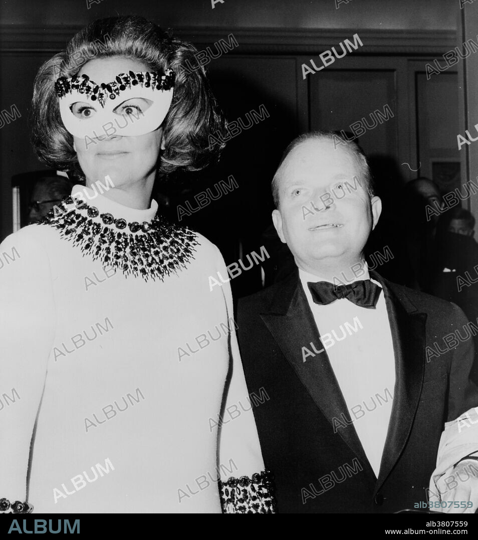 Capote enters party holding the hand of Katharine Graham who wears a decorative mask. Truman Streckfus Persons (September 30, 1924 - August 25, 1984), known as Truman Capote, was an American author, screenwriter, playwright, actor, many of whose short stories, novels, plays, and nonfiction are recognized literary classics. He earned the most fame with In Cold Blood, a journalistic work about the murder of a Kansas farm family in their home. A milestone in popular culture, In Cold Blood was the peak of Capote's literary career; it was to be his final fully published book. In the 1970s, he maintained his celebrity status by appearing on television talk shows. He died in 1984, at the age of 59, from liver cancer. Katharine Meyer Graham (June 16, 1917 - July 17, 2001) was an American publisher. She led her family's newspaper, The Washington Post, for more than two decades, overseeing its most famous period, the Watergate coverage that eventually led to the resignation of President Richard Nixon. Her memoir, Personal History, won the Pulitzer Prize in 1998. Photographed by Mel Finkelstein for New York World Telegram & Sun, 1966.