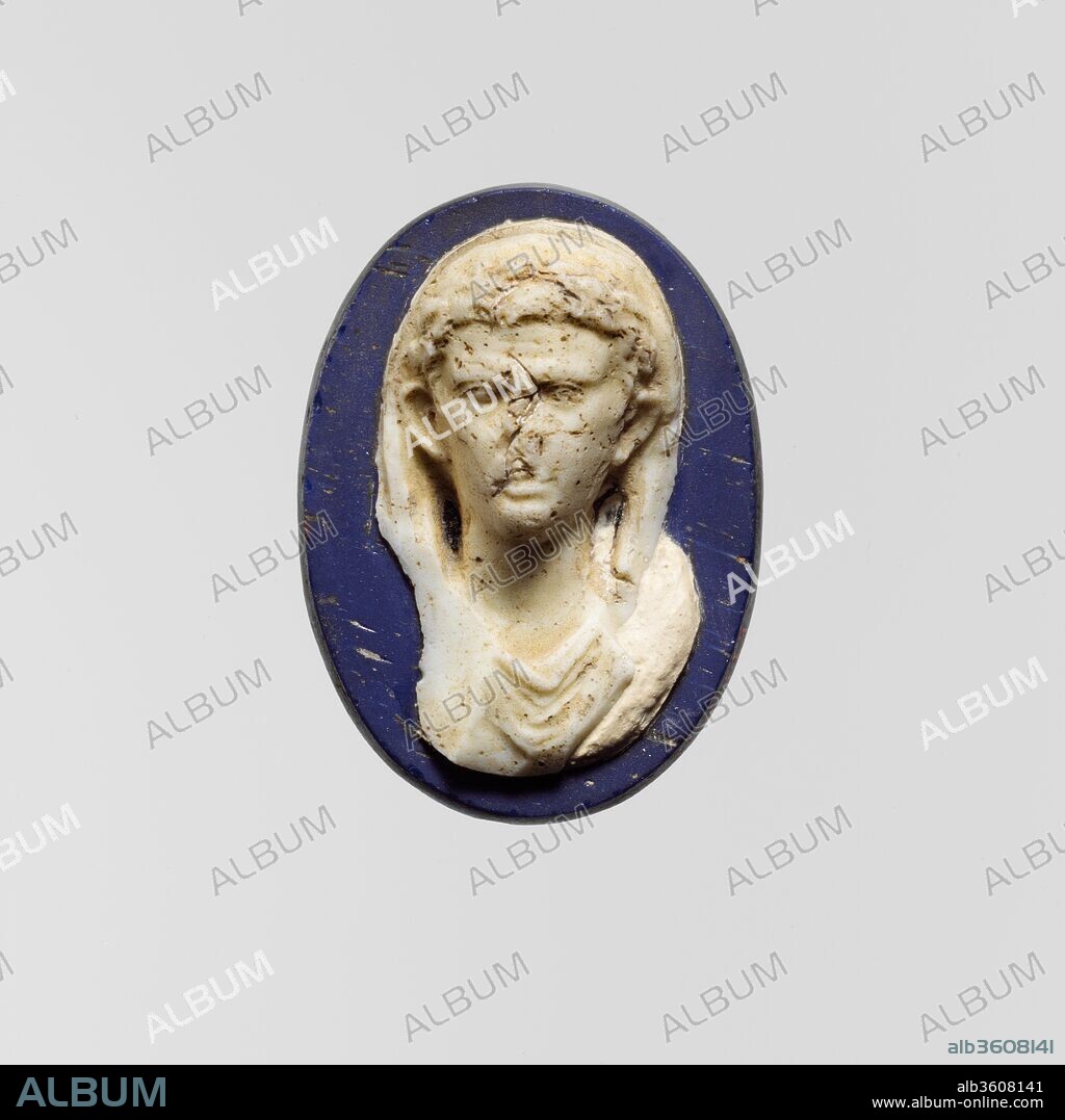 Cameo glass medallion of the emperor Augustus. Culture: Roman. Dimensions: H.: 1 11/16 x 1 1/4 x 1/2 in. (4.4 x 3.1 x 1.3 cm). Date: early 1st century A.D..
Matt cobalt blue, deep blue, almost opaque and appearing black, and opaque white.
Oval with slightly beveled, ground edge, flat back.
Decoration in high relief: bust of male shown frontally, with broad forehead, prominent ears, and clean-shaven features; on head, laurel wreath and chlamys that covers top of head and falls on either side of neck behind ears; below throat, toga hanging in folds.
Complete, but damaged with loss of nose and proper right side of bust; dulling and pitting, with small patches of faint creamy weathering.
The Emperor Augustus is shown with his head veiled as was the custom when about to perform a sacrifice.