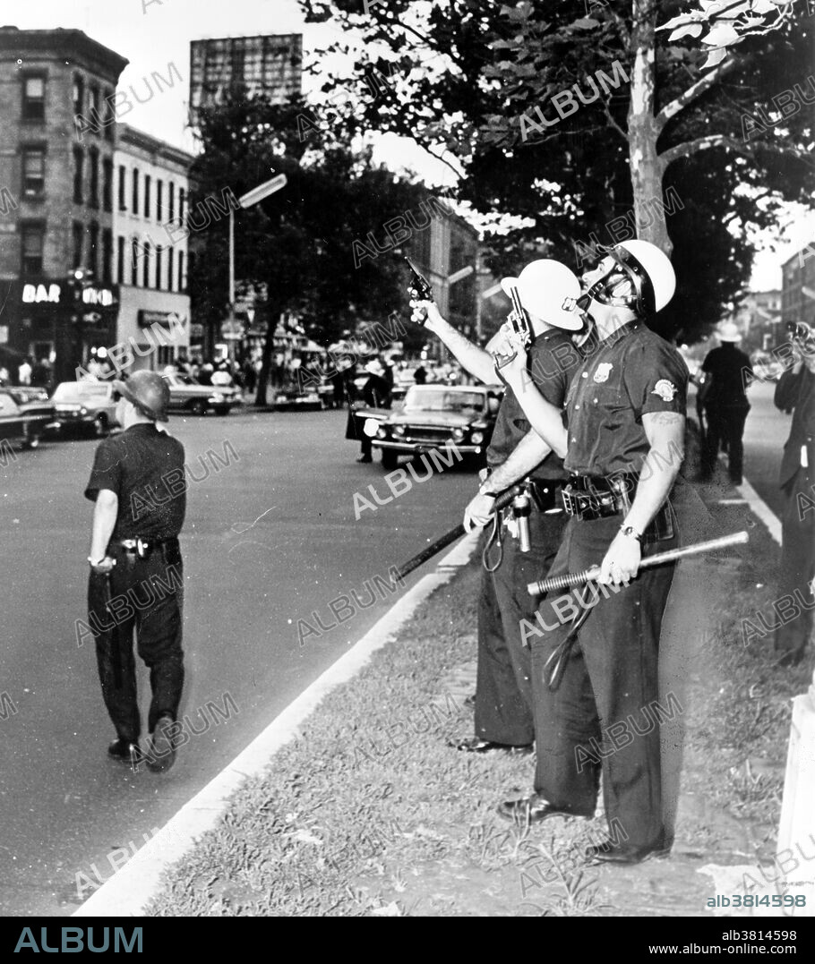 Entitled: "Police in Harlem standing on the street with guns drawn and pointing upwards during the July 1964 race riots." On Thursday, July 16, 1964, James Powell was shot and killed by police Lieutenant Thomas Gilligan. The second bullet of three fired by Lieutenant Gilligan killed the 15-year-old African American in front of his friends and about a dozen other witnesses. The incident immediately rallied about 300 students from a nearby school who were informed by the principal. This incident set off six consecutive nights of rioting that affected the New York City neighborhoods of Harlem and Bedford-Stuyvesant. In total, 4,000 New Yorkers participated in the riots which led to attacks on the New York City Police Department, vandalism, and looting in stores. At the end of the conflict, reports counted one dead rioter, 118 injured, and 465 arrested. Photographed for the New York World-Telegram & Sun by Stanley Wolfson, 1964.