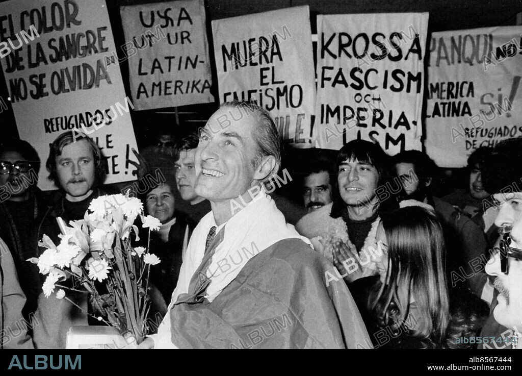 Stockholm 1973-12-10. Harald Edelstam, Sveriges ambassadör i Chile, insvept i den chilenska flaggan, möttes av chilenska flyktingar när han anlände till Arlanda . Foto: Jan Björsell / SvD / TT / kod 12014.