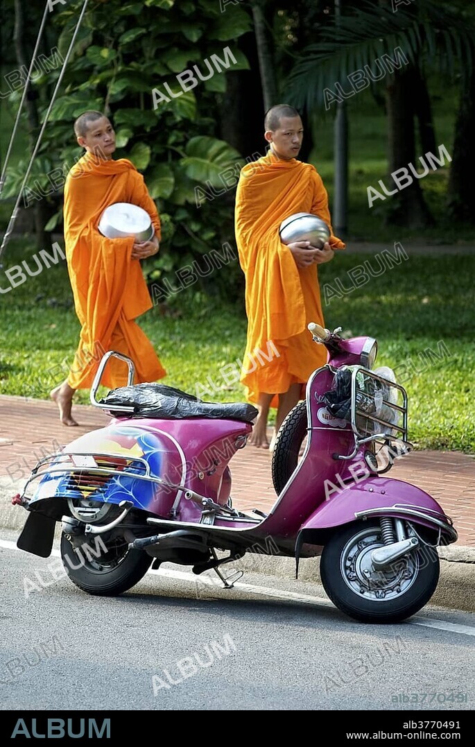 Buddhist monks collecting alms in the early morning and a Vespa scooter in Chiang Mai, Thailand, Asia.