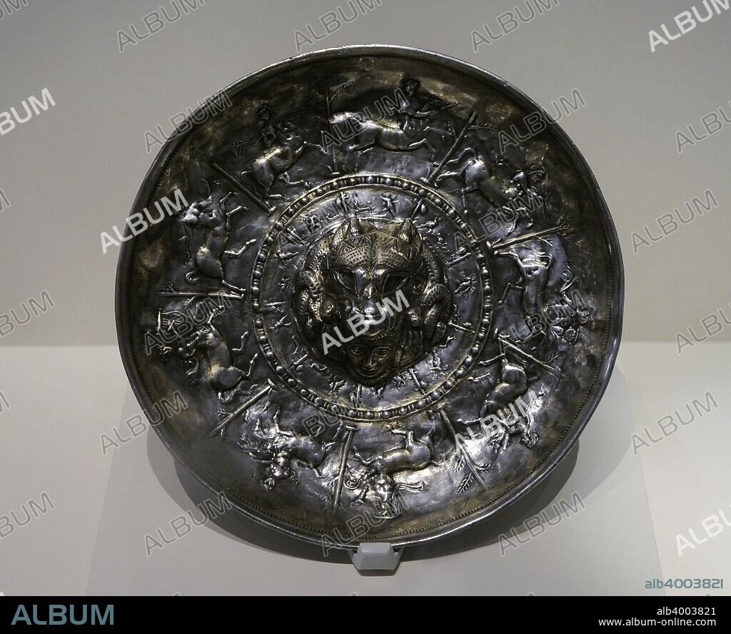 Cultura Ibérica. Tesoro de Perotito. Pátera para las libaciones. Segunda mitad del siglo III-principios siglo I a. C. Plata sobredorada. En el relieve se representa un lobo devorando una cabeza humana rodeada de serpiente. Alrededor, centauros y centauresas tocando instrumentos musicales y erotes con trofeos. Perotito (Santisteban del Puerto, provincia de Jaén, Andalucía). Museo Arqueológico Nacional. Madrid. España.