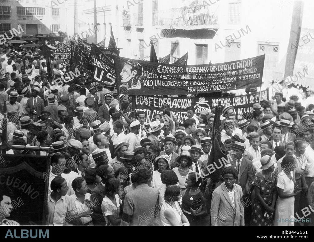 Orig. bildtext... CUBAN COMMUNIST HONORED THREE YEARS AFTER DEATH The remains of Julio Antonio Mella, Cuban political refugee who was killed in Mexico three years ago, supposedly at the behest of Ex-president Machado of Cuba. were exhumed from the resting place in Mexico to be buried on Cuban soil. Photo shows the large crowd that gathered to meet the ship which carried the body of Mella, and arrived in Havana, Sept. 26th. 9/27/33 Anm. J A Mella, 1903-1929, kubansk studentledare och en av det kubanska kommunistpartiets grundare. Kuba Halmhattar Banderoller Politisk opposition Trängsel CD678 persons: JULIO ANTONIO MELLA* sites: HAVANNA;CUBA.