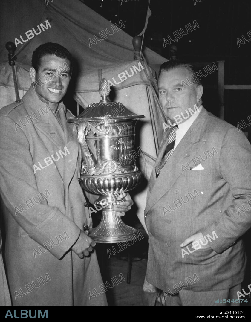 He Lost Cross-Channel Duel - Abdel Latif Abu Heif, of Egypt, winner of the Butlin International cross-channel race, is presented with the 1,000 guineas "Butlin cup" by Mr. Billy Butlin at Folkestone swimming pool a short while after the race had finished. A thrilling stroke-by stroke due ***** Two exhausted swimmers ended yesterdays cross-channel race. They struggle ***** last two miles with only a few year between them. Fifty yards off the shore ***** Dover and Folkstone, the 27-year-old Egyptian, Abdel Abu Helf, began a mighty last effort flinging himself forward in the - energy -sapping butterfly stroke. a few minutes later he climbed onto the rocks, the winner, with a time of 11 hours 44 minutes. August 16, 1955. (Photo by Paul Popper; Paul Popper Ltd.).
